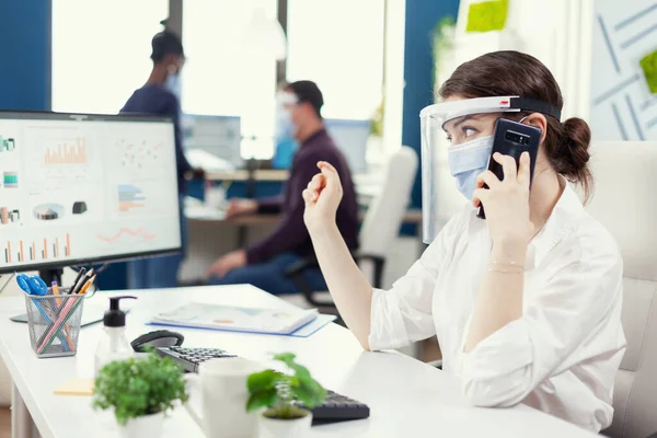 Administradora de negocios sentada en su lugar de trabajo usando mascarilla facial durante covid 19 —  Fotos de Stock