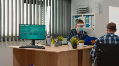 Yüz maskesi takan engelli işçi konuşuyor.