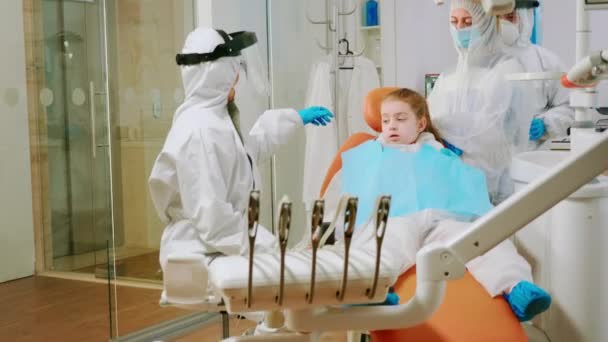 Tandarts met coverall houden mond x-ray beeld kind patiënt praten — Stockvideo