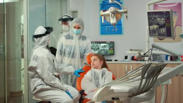 Pediatric dentist and nurse in ppe suit interrogating kid patient — Stock Video