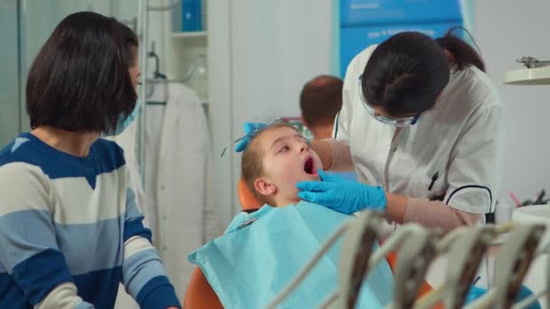 小さな女の子患者へのマスク治療歯を持つ小児歯科医 — ストック動画