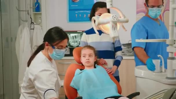 Medico odontoiatrico che parla con un bambino seduto sulla sedia stomatologica — Video Stock