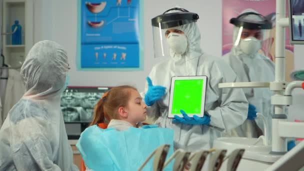 Dentista con protector facial apuntando a la pantalla verde hablando con el niño — Vídeos de Stock