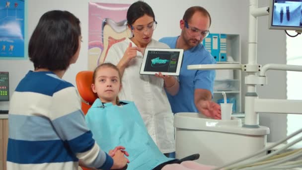 Stomatolog som pekar på digital skärm och förklarar röntgen för mamma — Stockvideo