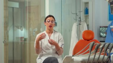 Kadın stomatolog video kamerada konuşuyor.