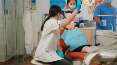 Küçük hastayı muayene eden dişçi teknisyeni.