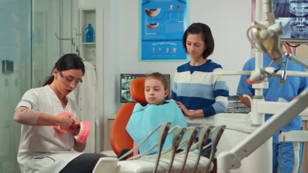 Estomatologista explicando a criança higiene dentária adequada usando esqueleto de dentes — Vídeo de Stock