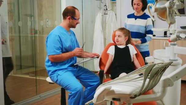 Nurse taking notes on clipboard about little girl dental problems — Stock Video