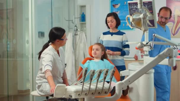 Estomatólogo médico explicando a la madre el proceso dental de intervención — Vídeo de stock