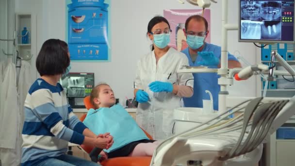 Dokter gigi pediatrik dengan topeng memeriksa kesehatan gigi seorang gadis kecil — Stok Video