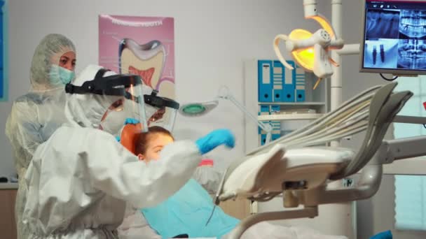 Bambina che indossa tuta ppe guardando allo specchio dopo l'intervento dentale — Video Stock