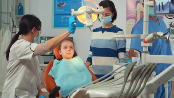 Médico dentista pediatra trabajando en unidad dental con enfermera y niña pequeña paciente — Vídeos de Stock