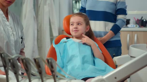 Közelkép egy fogfájós gyerekről, aki fogselymet visel és fogorvossal beszélget. — Stock videók