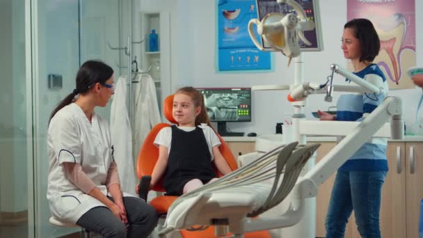 Μικρό κορίτσι ασθενής με πόνο στα δόντια εξηγώντας οδοντιατρικό πρόβλημα στον παιδιατρικό οδοντίατρο — Αρχείο Βίντεο