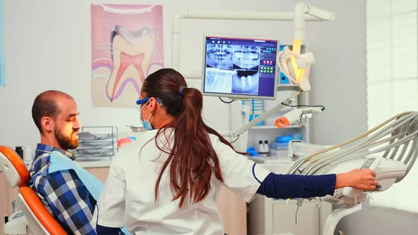 Стоматолог-врач зажигает лампу осматривая пациента — стоковое фото
