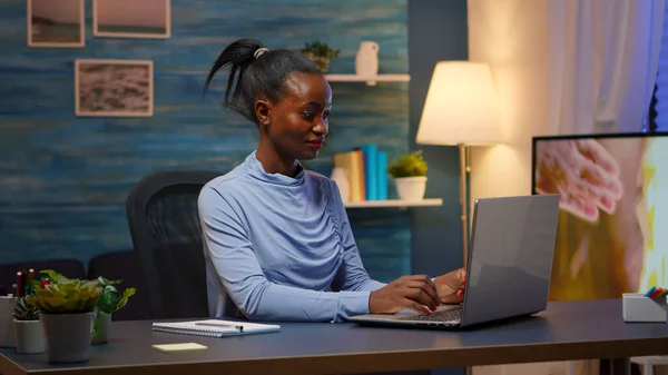 Mulher negra digitando no computador sorrindo tarde da noite — Fotografia de Stock