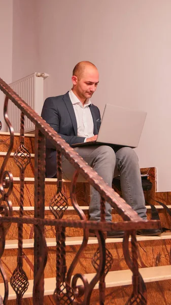 Firmenchef arbeitet mit Laptop im Treppenhaus — Stockfoto