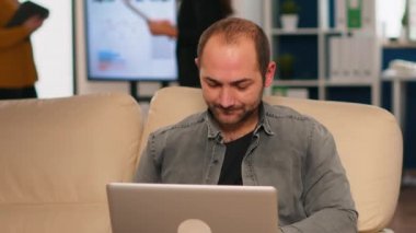 Müdür koltukta oturmuş kameranın önünde gülümsüyor.