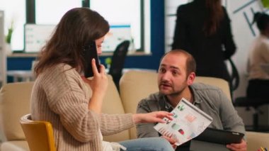 Erkek, kadın akıllı telefondan konuşurken kadın yöneticiye grafikleri soruyor.