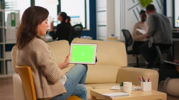 Vista posterior de la mujer de negocios sentada en el sofá utilizando la tableta con pantalla verde — Vídeos de Stock