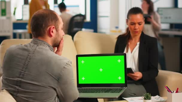 Бізнес команда сидить на дивані аналізуючи графіки, тримаючи ноутбук з маком — стокове відео