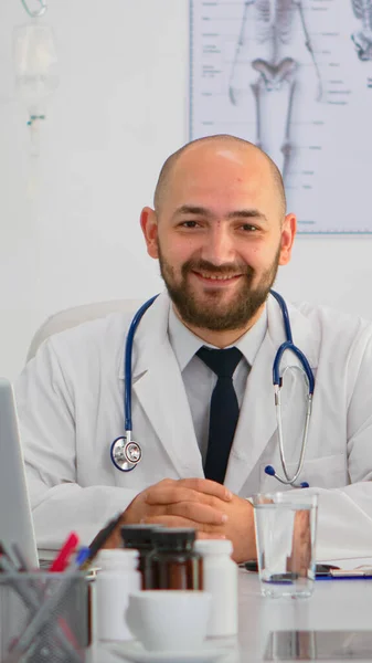 Dokter kijkt naar camera glimlachend tijdens brainstormen — Stockfoto