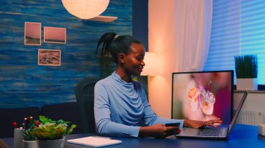 Siyah iş kadını kredi kartıyla evden alışveriş yapıyor.