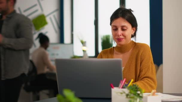Wesoła biznesmenka pisząca na laptopie i uśmiechnięta siedząca przy biurku — Wideo stockowe