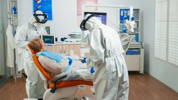 Dentiste en équipement de protection examinant les rayons X à l'aide d'un comprimé — Photo