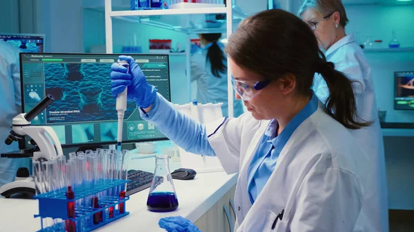 Chemist putting liquid in test tube with micropipette —  Fotos de Stock