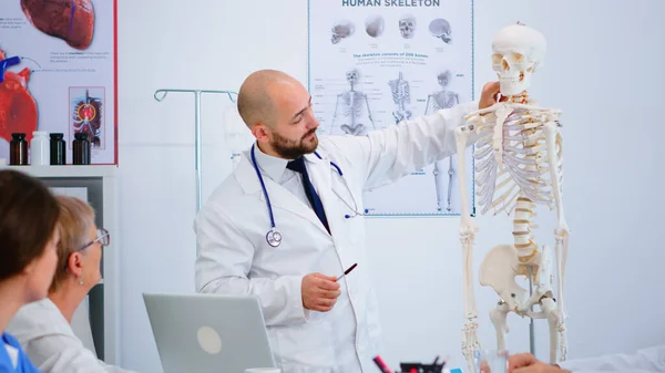 Specialistläkare som visar kroppens benfunktion med hjälp av skelettmodell — Stockfoto