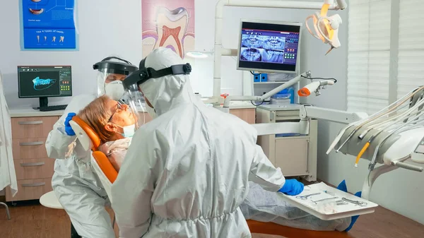 Медсестра и врач в защитном костюме работают в стоматологическом отделении — стоковое фото