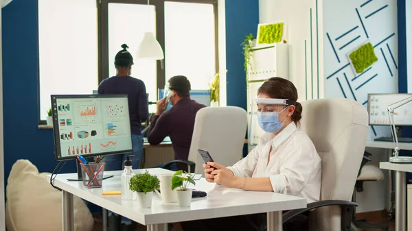 Businesswoman with mask chatting using phone in office room — Stock Photo, Image