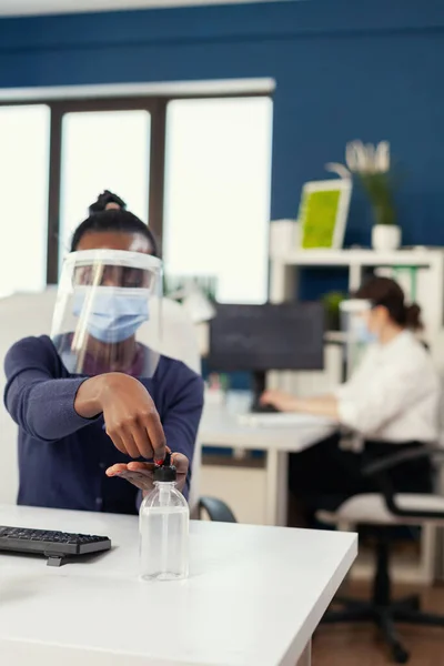 African woman in corporation office applying hand sanitizer — Stock Photo, Image