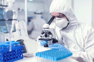 Yüz maskesi takmış odaklanmış sağlık araştırmacısı.