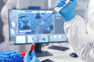 Tıbbi araştırmacı test tüpüne kan damlatıyor.