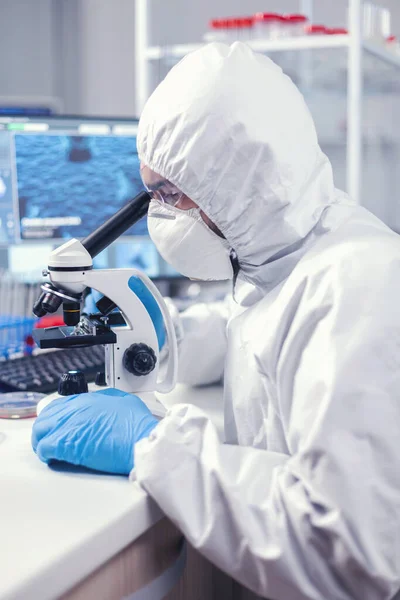Медик во время глобальной пандемии работает на микроскопе — стоковое фото