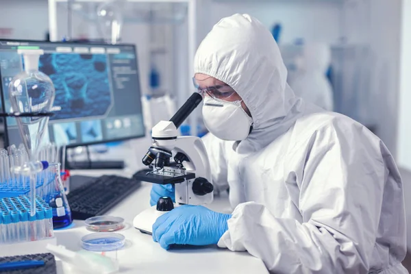 Биохимик в защитном костюме работает в лаборатории — стоковое фото