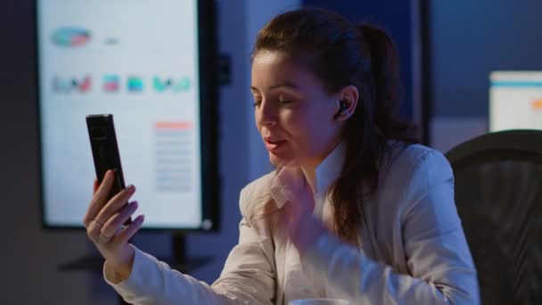 Предприниматель, проводящий виртуальную встречу с использованием смартфона с беспроводными наушниками — стоковое видео