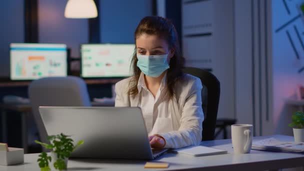 Employee with protection face mask working late at night in new normal office — Stock Video