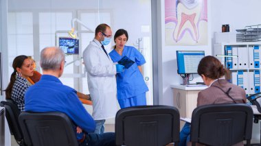 Doktor diş röntgeni tutan asistanla konuşuyor.