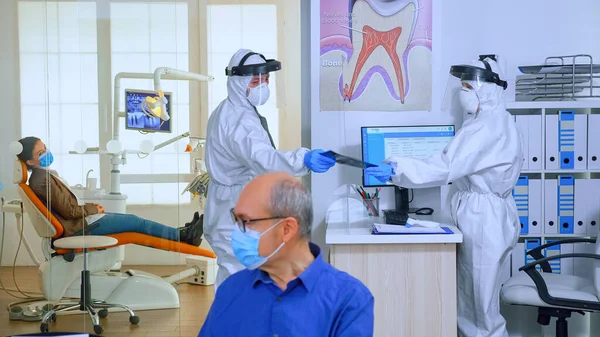 Стоматолог в защитном костюме просит пациента сделать рентген зубов — стоковое фото