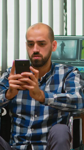 Videoredakteur im Rollstuhl textet auf Smartphone — Stockfoto