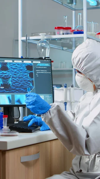 Химик с покрытием смотрит на вирусные тесты в оборудованной лаборатории — стоковое фото