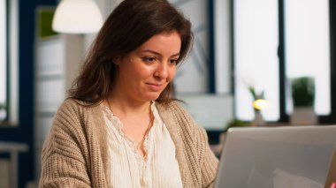 Lapotop 'un önündeki masada oturan mutlu otantik çalışanın e-postalarını kapat.