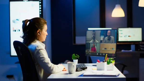 Empresária conversando durante videoconferência com equipe à meia-noite — Fotografia de Stock