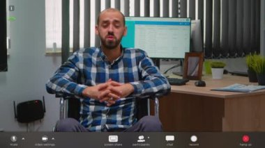 Tekerlekli sandalyedeki engelli işadamı video çağrısına el sallıyor