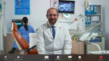 Dişçi hastalarla çevrimiçi konuşurken kameraya bakıyor