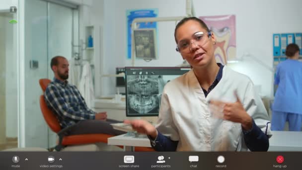 Стоматолог-врач разговаривает с пациентами через веб-камеру — стоковое видео