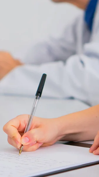 Sluiten van verpleegkundige schrijven op klembord tijdens medische vergadering — Stockfoto
